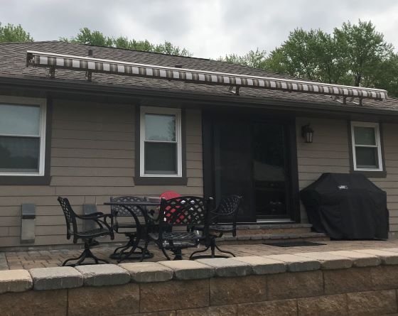 Wide retractable porch awning fully extended across a Kansas City back porch with no front support posts