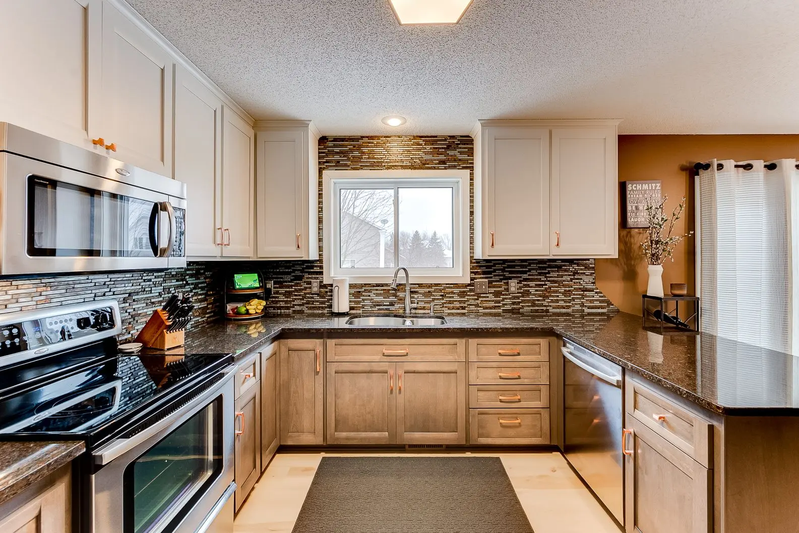 Modern kitchen featuring brown wood lower cabinets, white upper cabinets, and a mosaic tile backsplash.